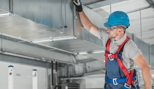 HVAC technician does preventative HVAC maintenance on air duct thanks to IoT-enabled HVAC technology