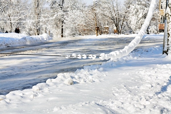 Heavy snow bows an electrical line over a sidewalk