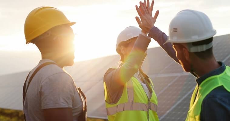 Three green energy electricians high five on a sunny day