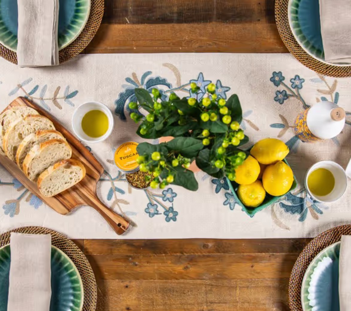 Ruggable Rustic Rivera press mailer styled as a tablescape with a floral runner, lemons, olive oil, and sliced bread