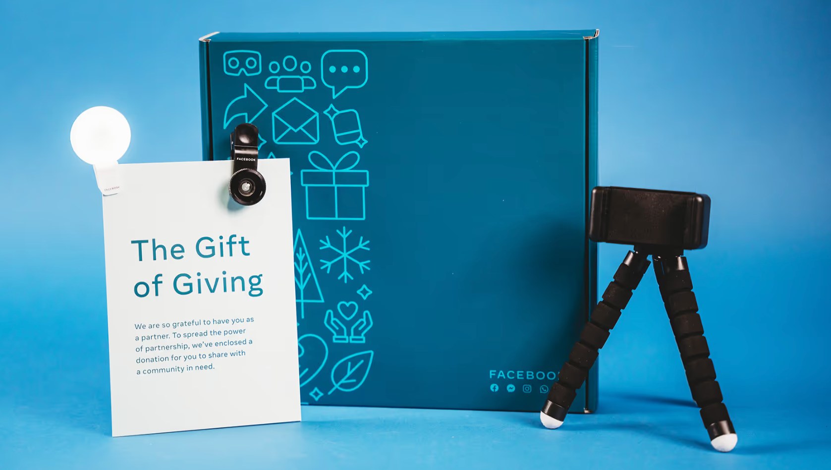 Meta holiday gift box in teal with a The Gift of Giving card, clip-on selfie light, and flexible phone tripod