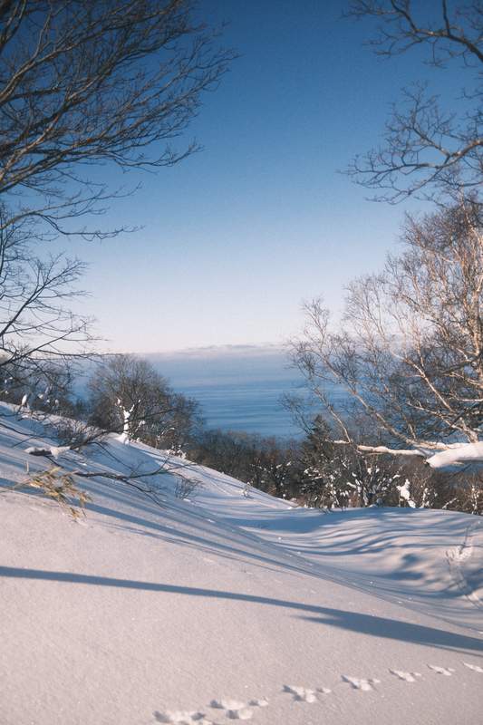 A landscape view from a snowy hill down to the ocean in the Hokkaido island.