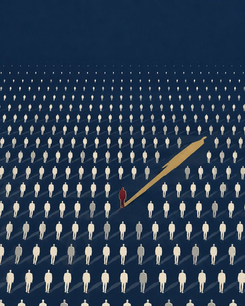 A lone oxblood figure stands upright among endless rows of identical cream figures, casting a long gold shadow