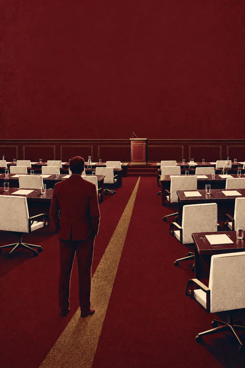 A lone oxblood figure stands in an empty summit room after everyone has left