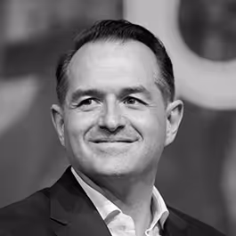 Black and white headshot of Brian Garish in a suit, smiling slightly to the side
