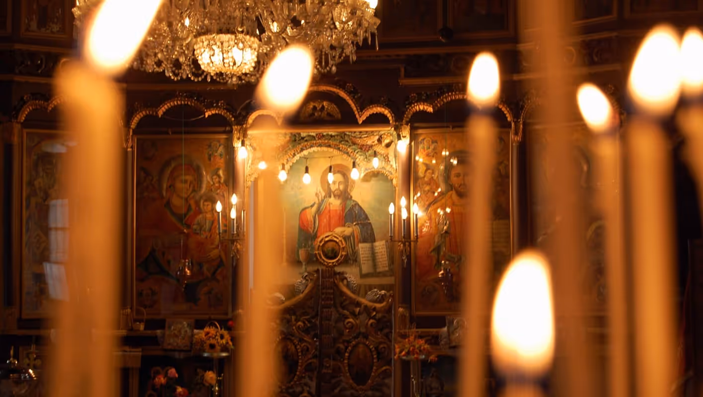 Candles illuminated before a beautiful golden icon of Jesus Christ in a church.