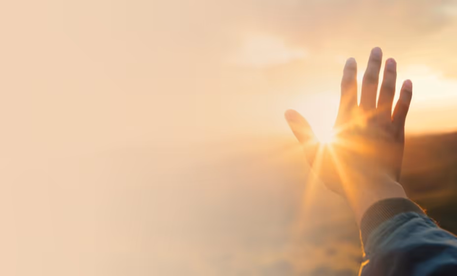 Raised hands reaching toward the sunrise - symbol of prayer, hope and the journey to Christian faith.