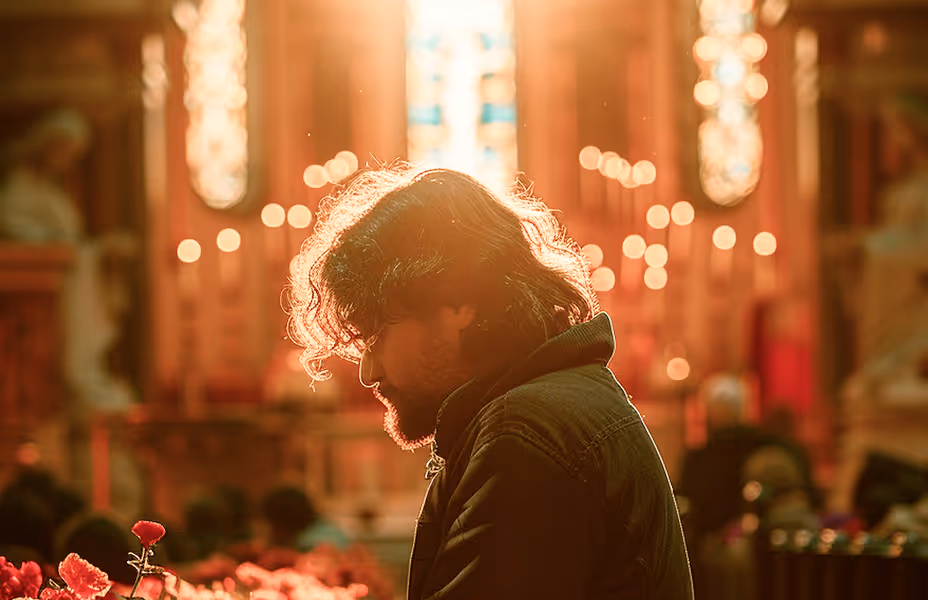 Man in quiet prayer before candles and icons in an Orthodox church, bathed in warm backlight to evoke personal devotion, repentance, and contemplative worship.