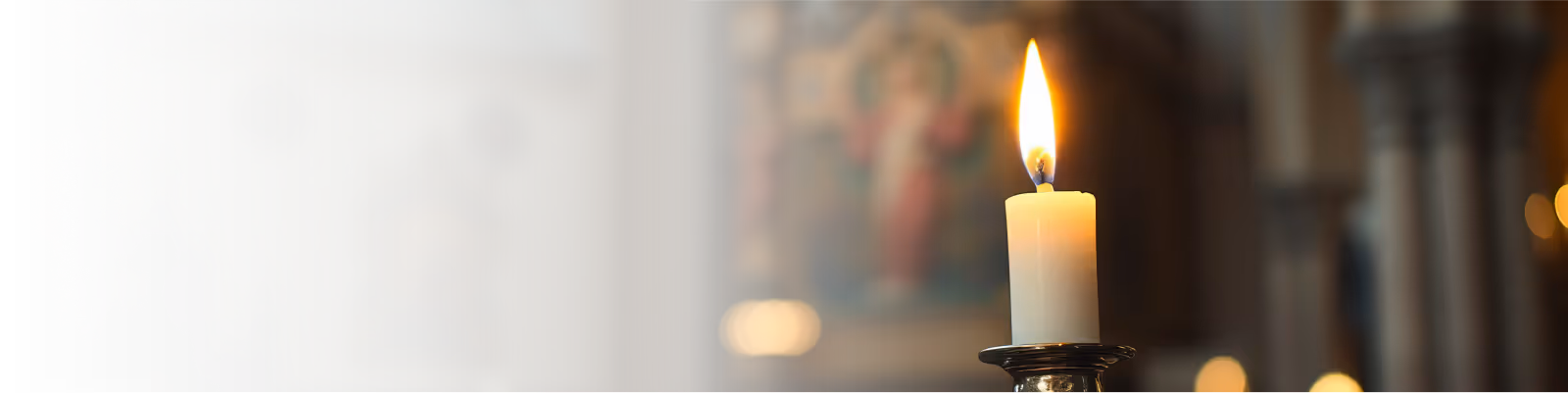 Orthodox Christian lit candle on a silver holder in a prayerful church atmosphere.