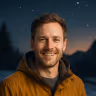 Mark Evans, 29, smiling in snowy Denver at dusk—portrait for his ‘saved in a car accident’ testimony.