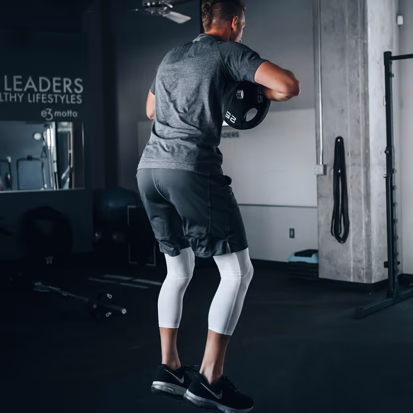 A man in a gym holding a weight.