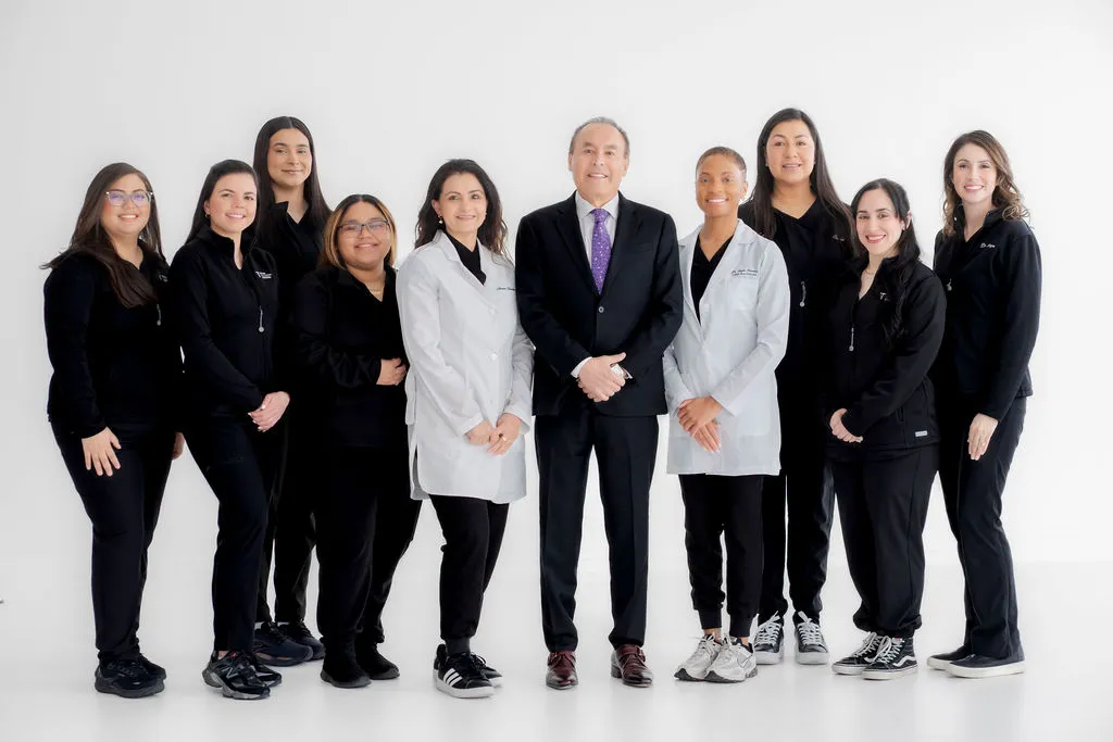 Group photo of the medical and administrative staff of Texas Dizziness Center, consisting of ten professionals in lab coats and scrubs, smiling confidently.