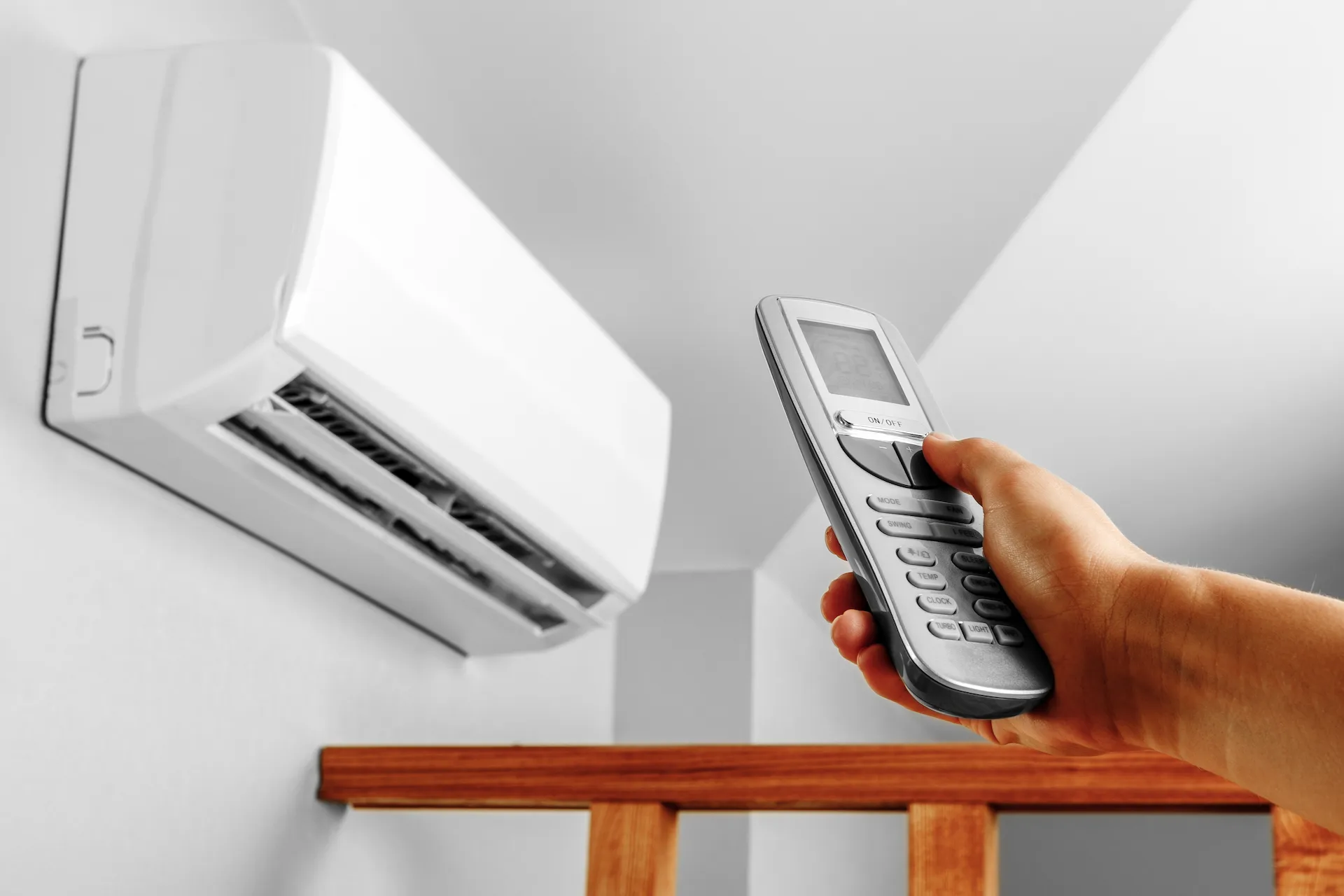 Télécommande pointée vers une unité de climatisation murale moderne dans une pièce