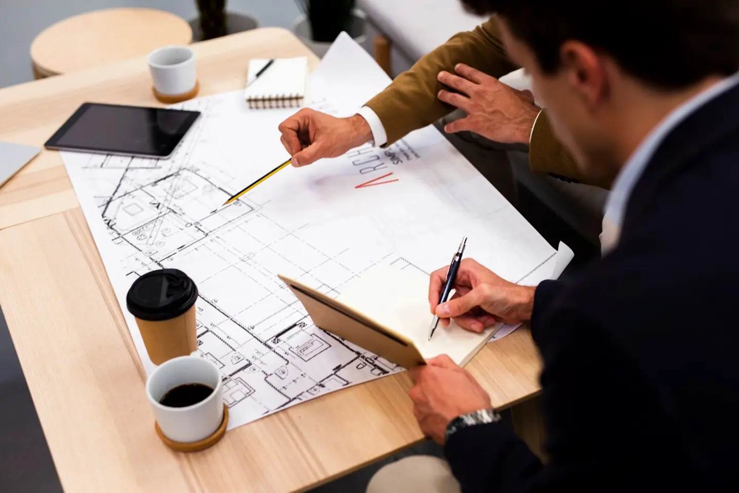 Deux professionnels discutant autour d'un plan d'architecture, symbolisant l'accompagnement sur-mesure de Primo Énergie pour vos projets de rénovation énergétique