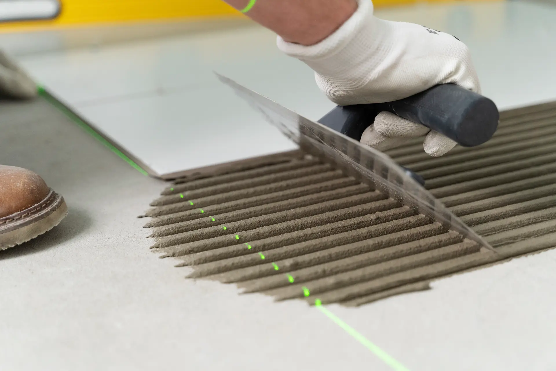 Application de colle à carrelage avec alignement laser pour une pose droite