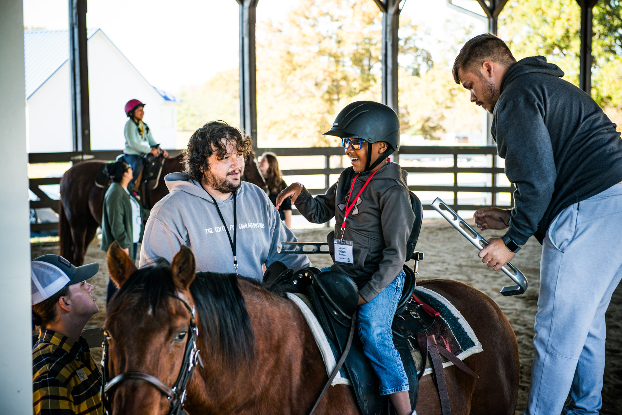 Volunteer helping camper ride a horse