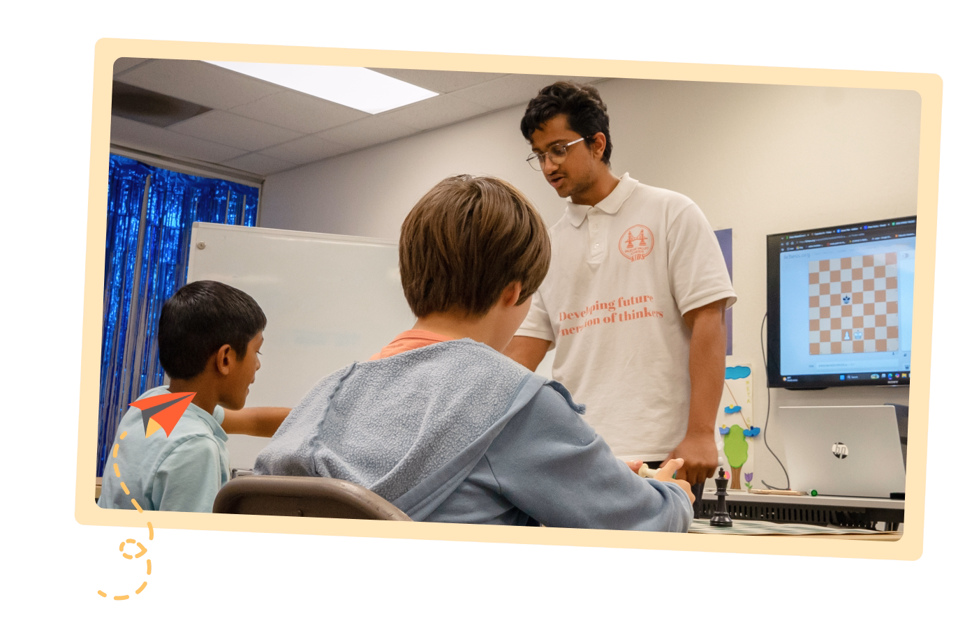 A coach trained under SVC Academy is teaching a group of students in a classroom about chess.