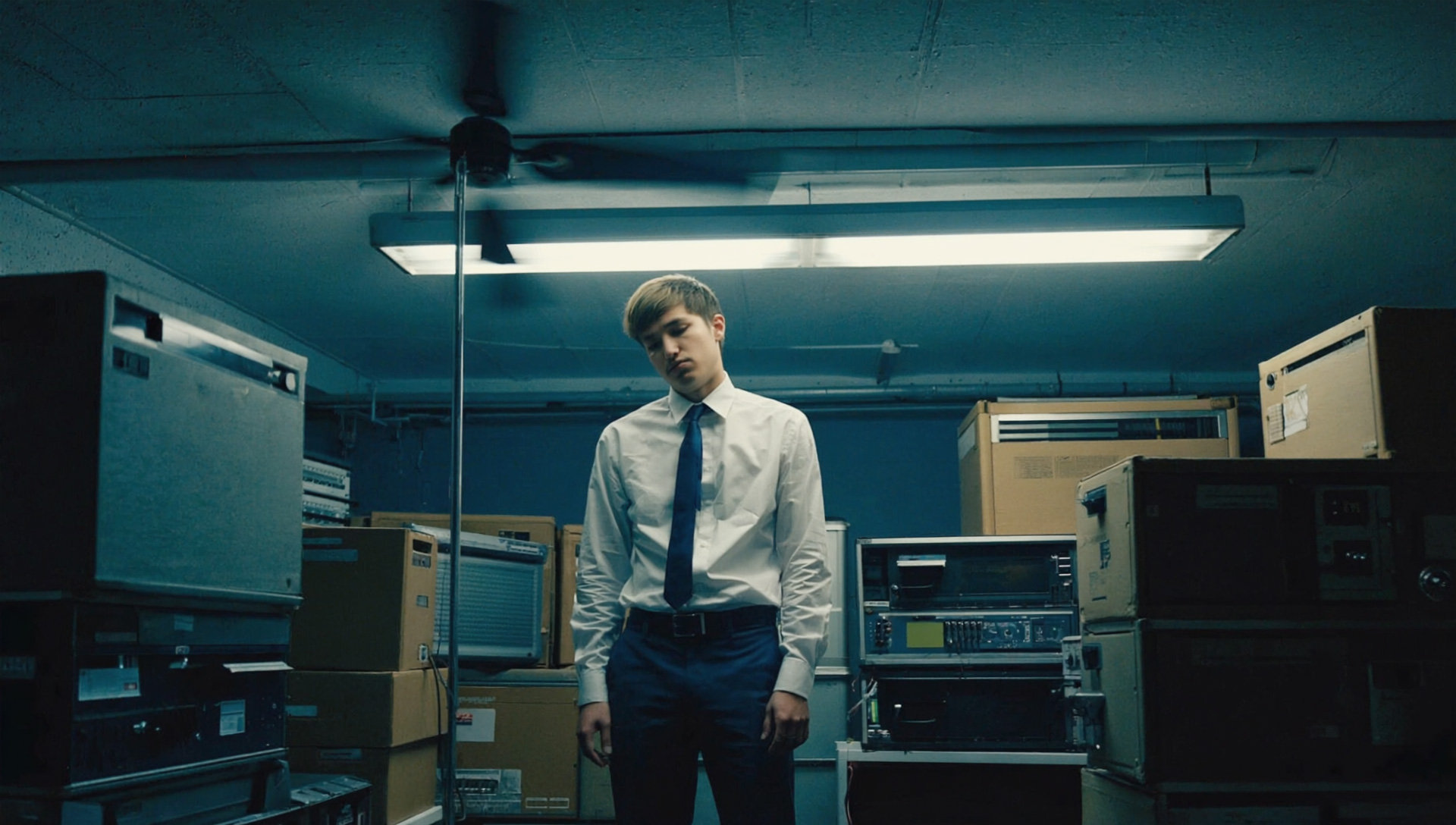 sad solemn man in office storeroom with equipment standing in the middle