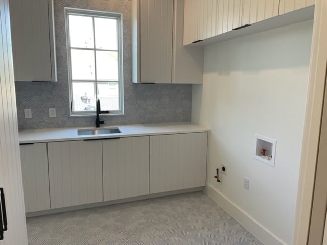 Modern laundry room with built-in cabinets, a sink, and washer-dryer hookups.