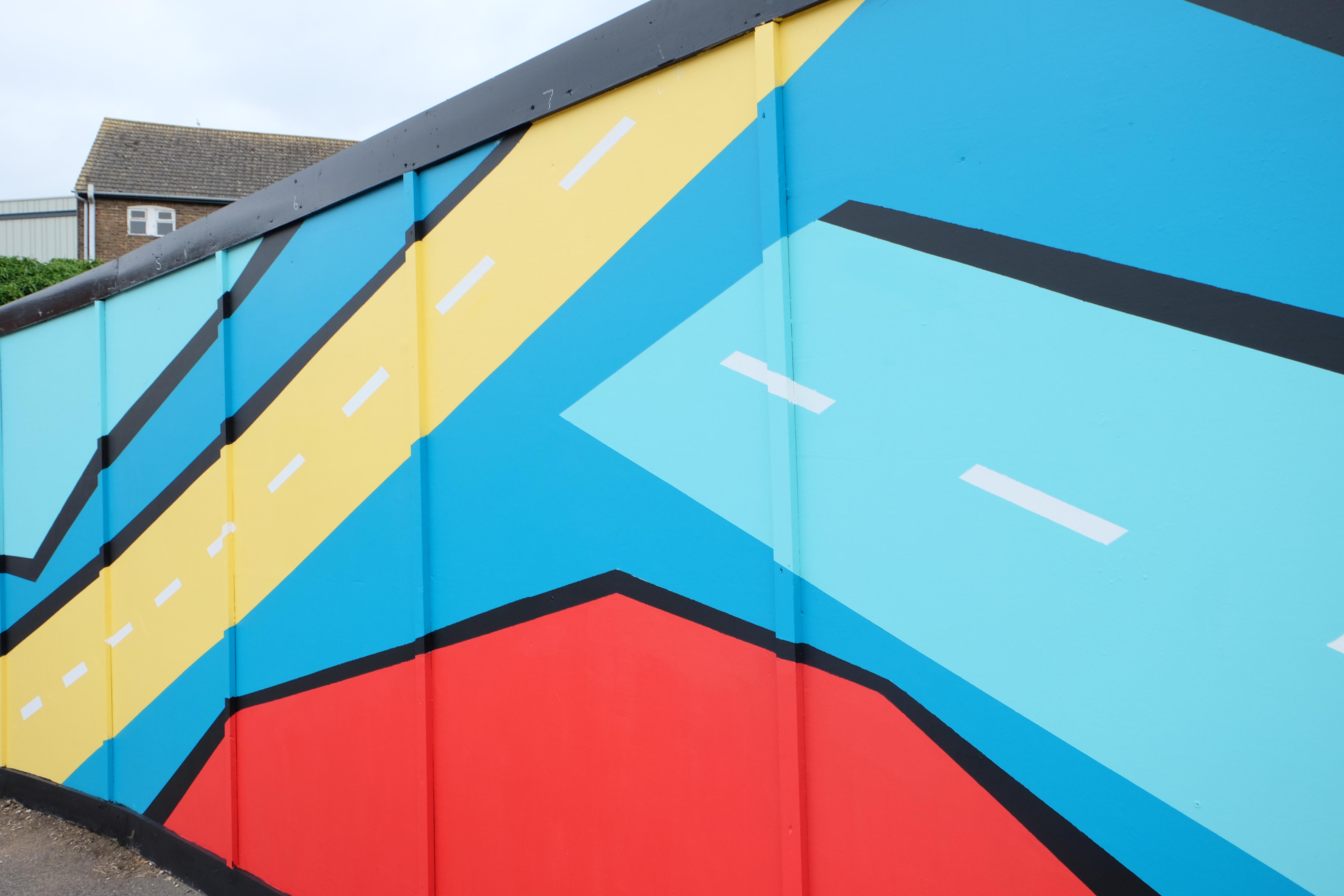Artists hand-painting the outdoor mural installation in Sittingbourne on hoarding boards