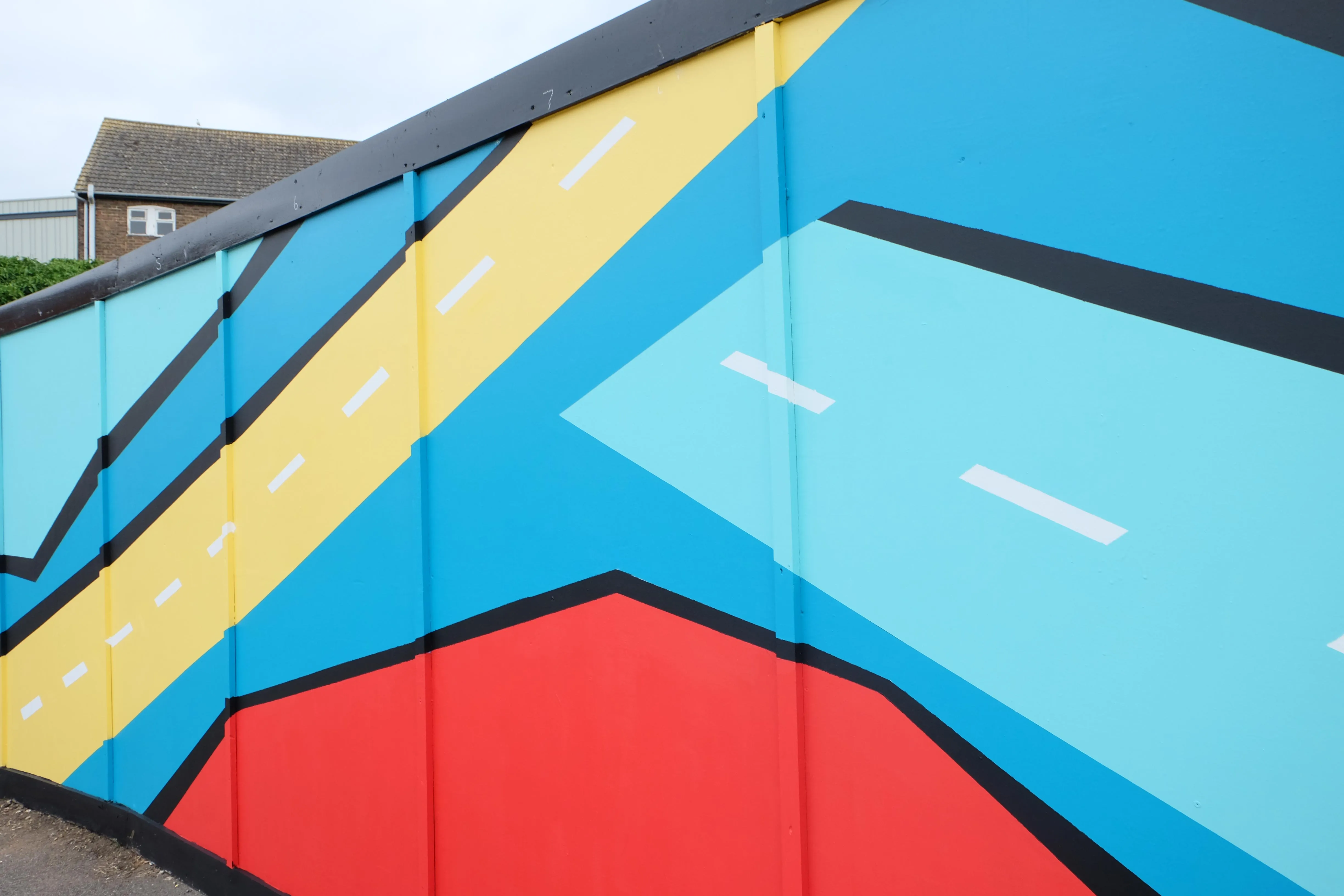 Artists hand-painting the outdoor mural installation in Sittingbourne on hoarding boards