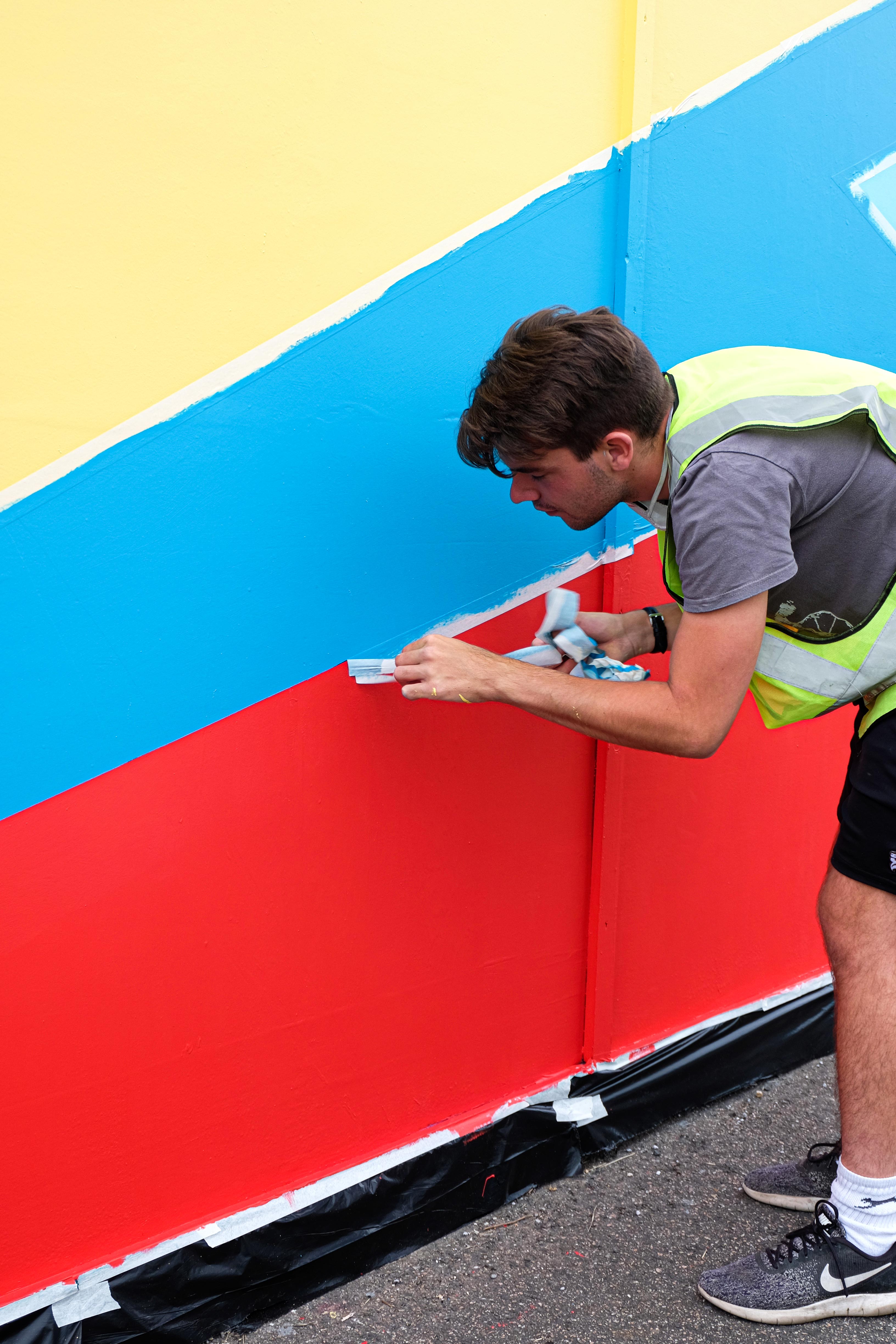 Artists hand-painting the outdoor mural installation in Sittingbourne on hoarding boards