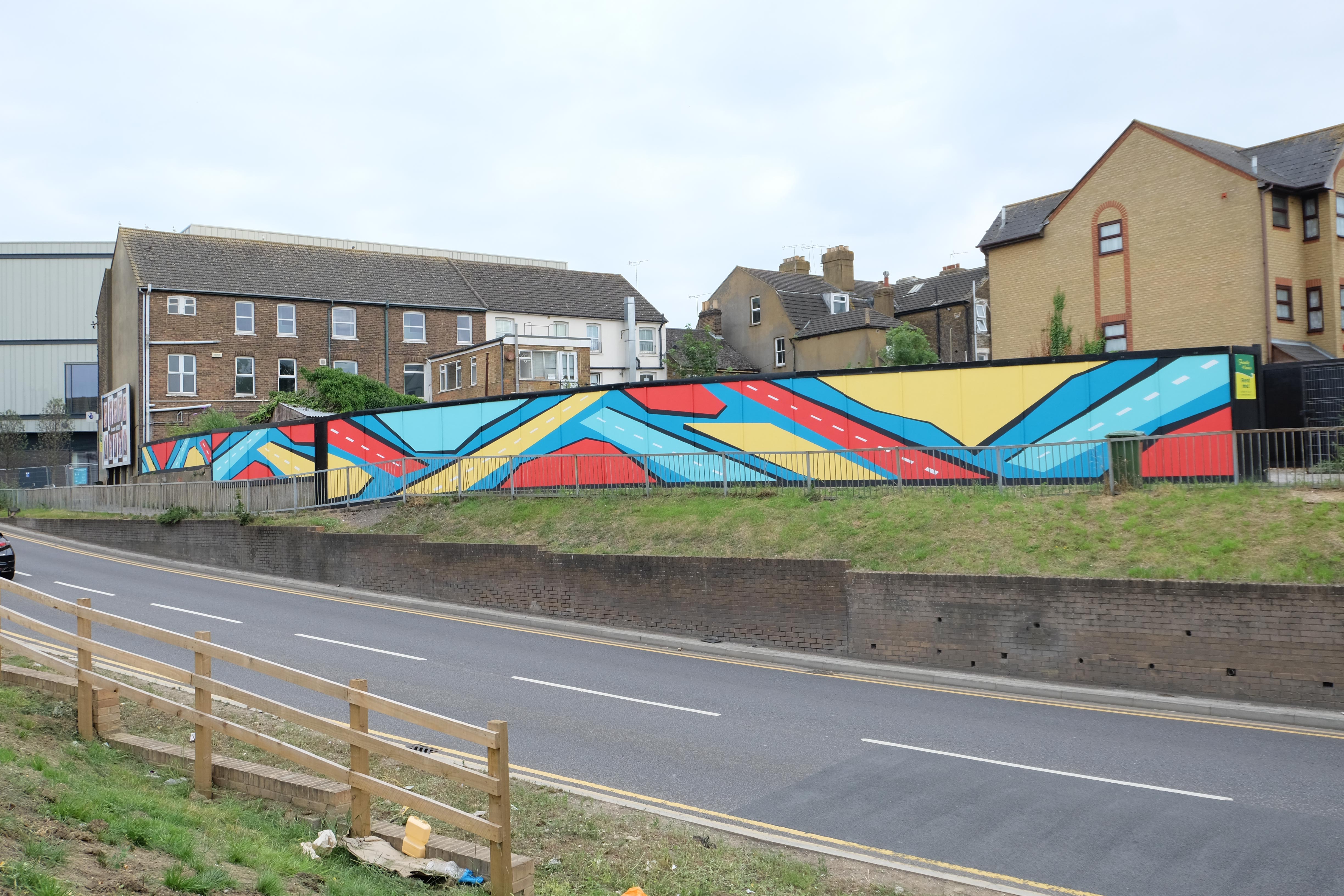 Completed mural installation in Sittingbourne showing full hoarding stretch with vibrant colours