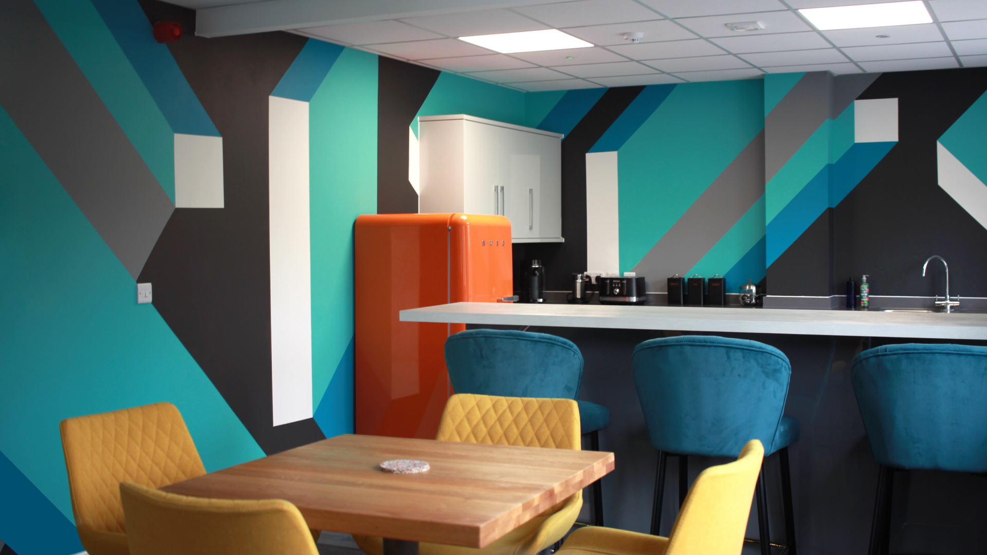 Completed mural artwork installed in FORTH's modern office space, featuring bold geometric patterns aligned with the company's branding.