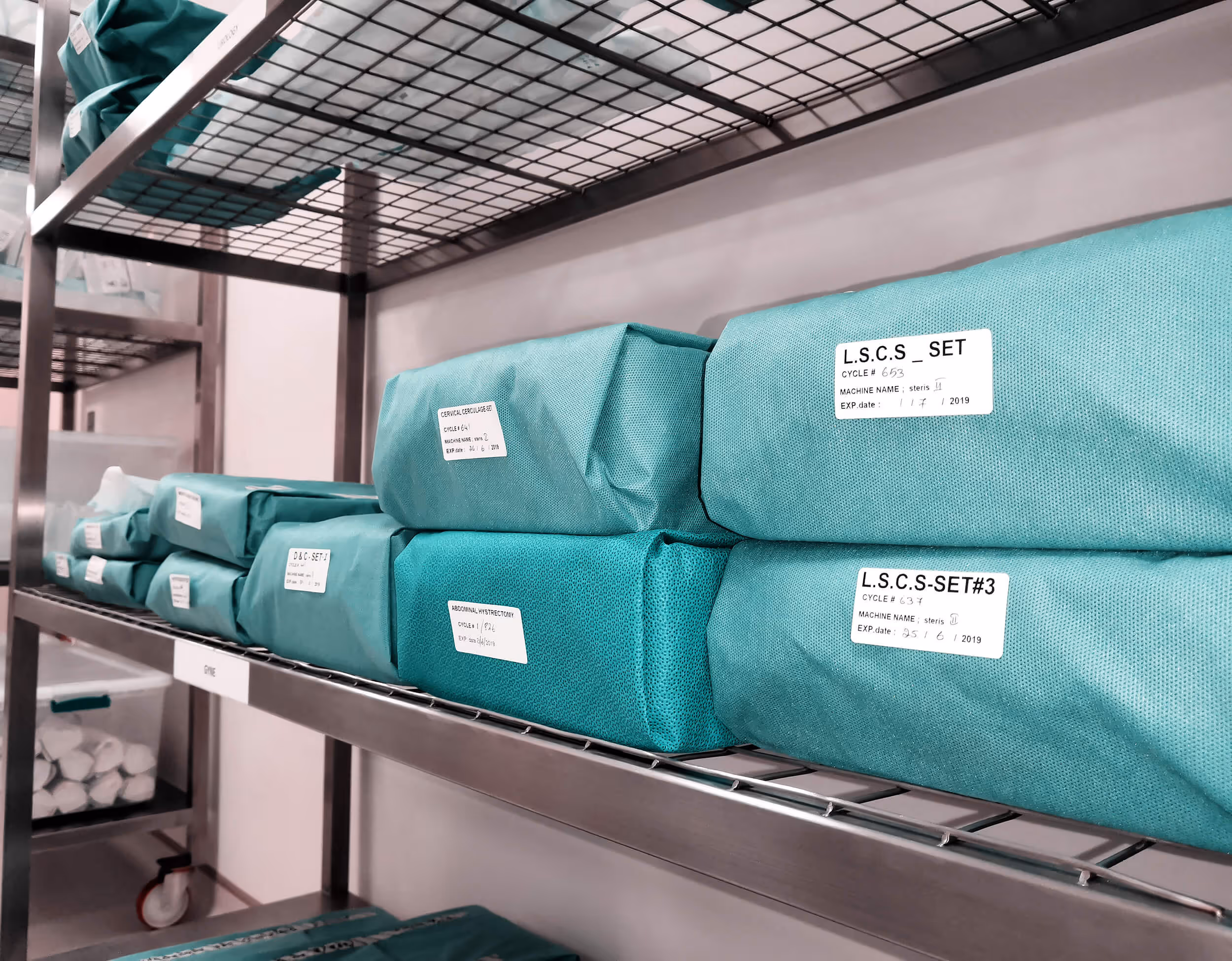 Green medical supply packages labeled and organized on metal shelves in a storage room.