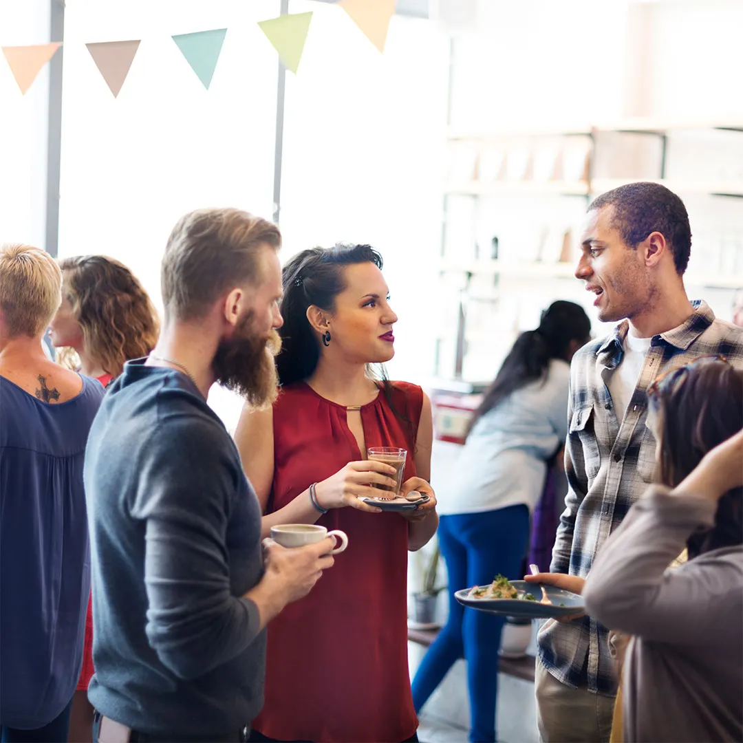 Persone che conversano e bevono insieme durante un evento sociale in un ambiente interno illuminato.