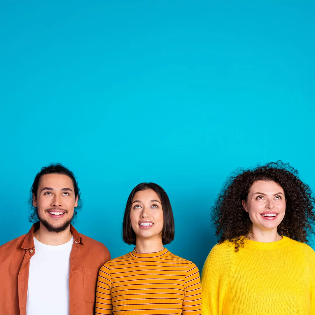 Tre persone sorridenti, due donne e un uomo, guardano verso l'alto su uno sfondo blu.