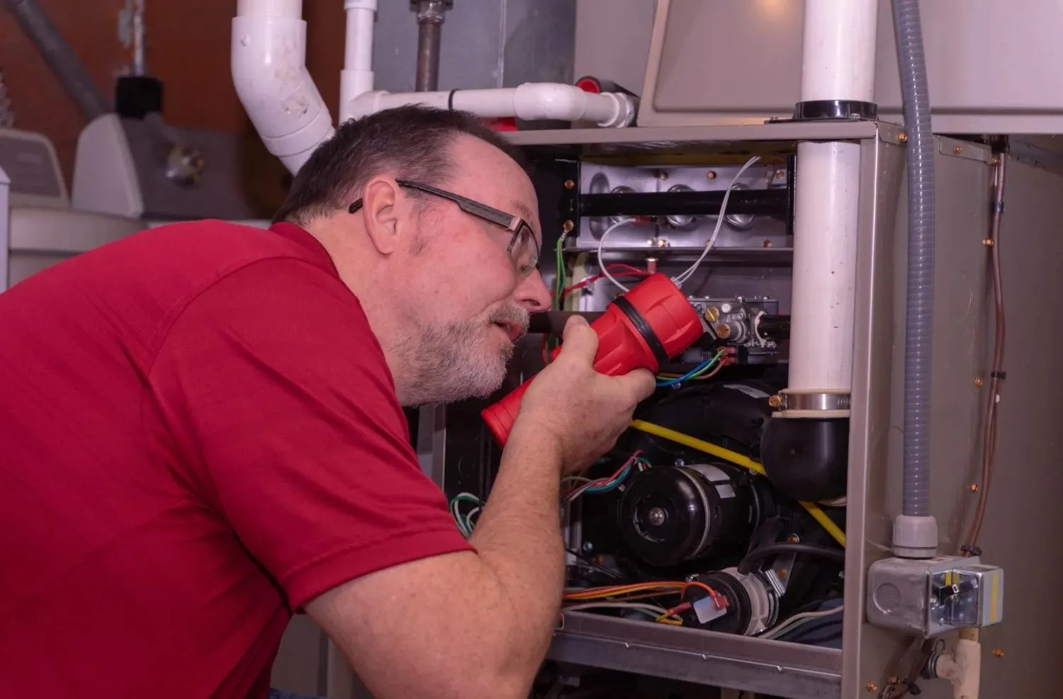 Man in red shirt inspecting furnace wiring