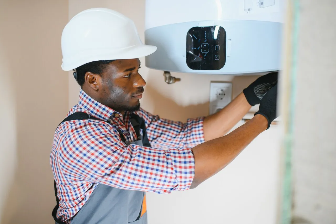 A Technician with white hard hat replacing a water heater.