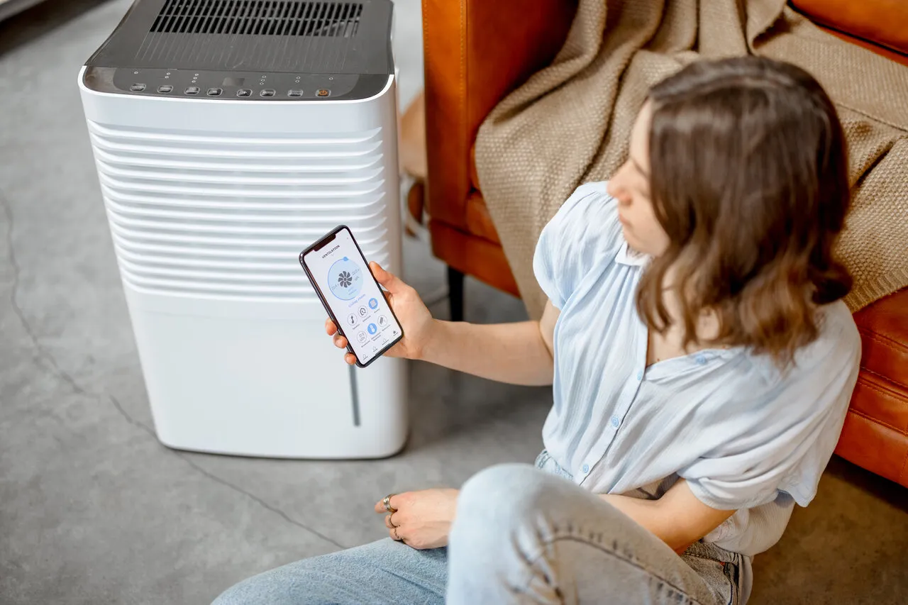Woman adjusting smart evaporative cooler with phone
