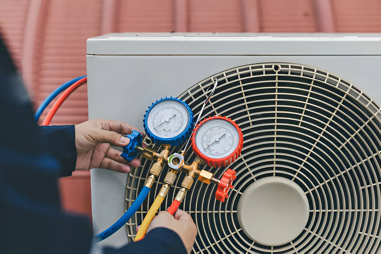 "Technician checking an outdoor AC unit with gauges"