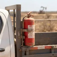 Detalhe do extintor preso por cintas ao suporte metálico