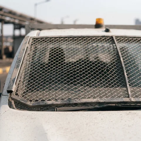 Detalhe da malha metálica da tela do para-brisa com a moldura de aço