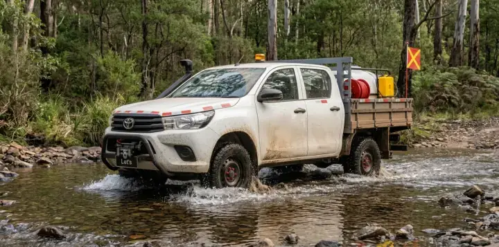 Picape com snorkel atravessando um córrego raso em estrada florestal