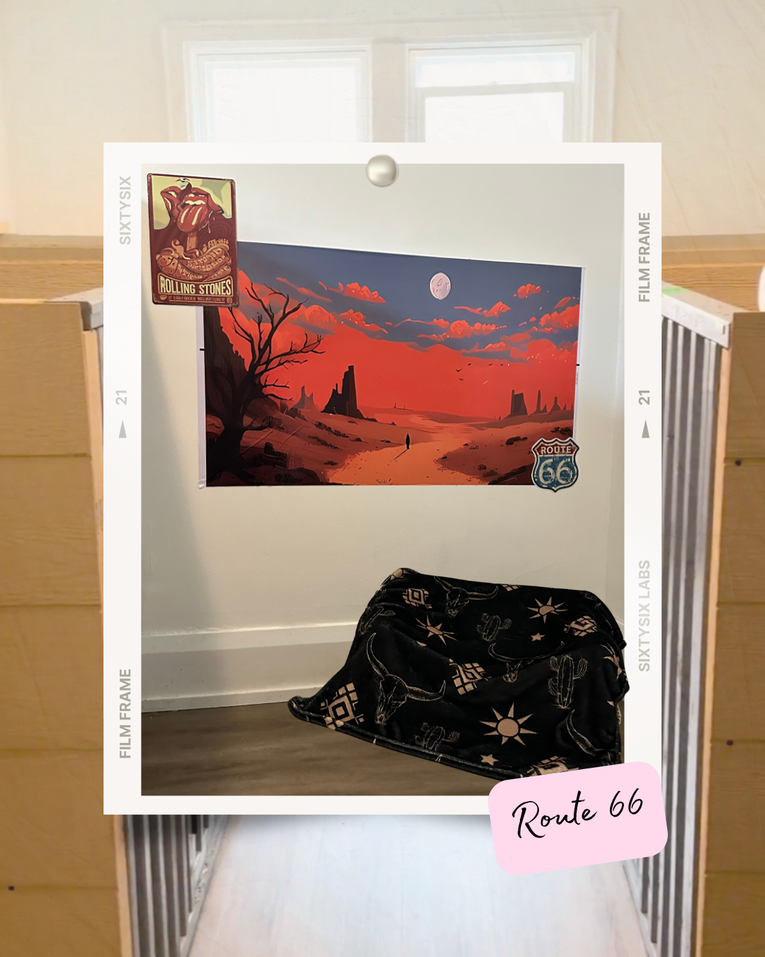 Wall poster of a red desert landscape with a Route 66 sign and a blanket with Western motifs on the floor.