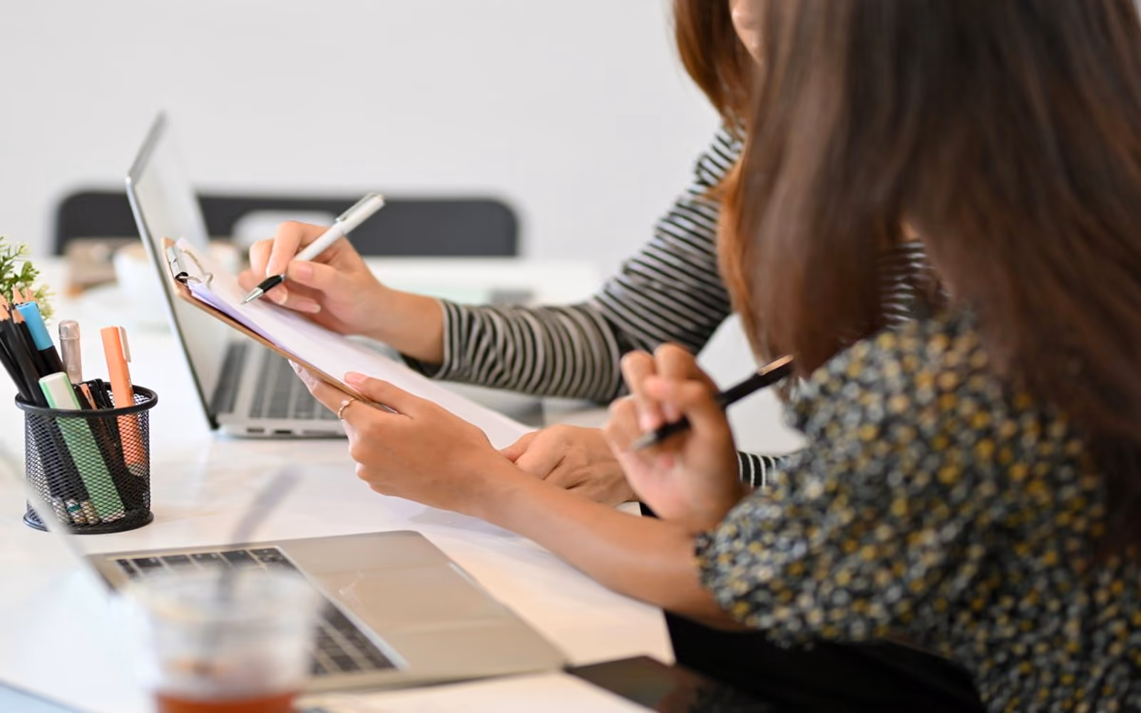 Two colleagues reviewing notes on a clipboard together
