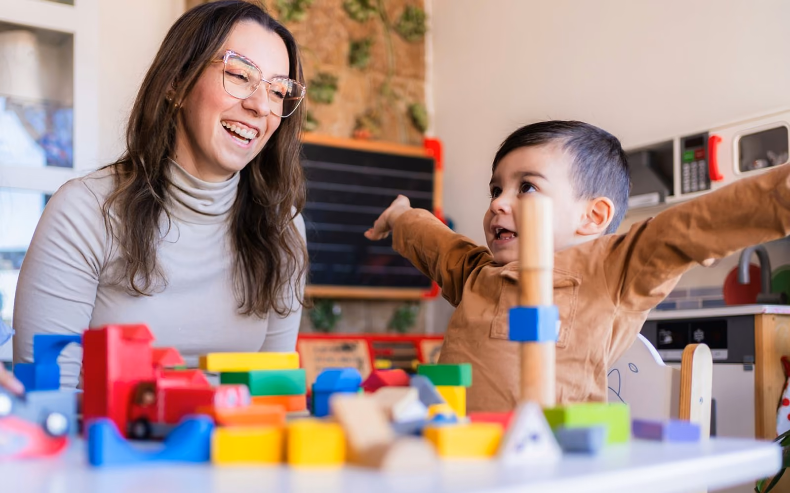 Clinician smiling while working with a young learner at a table of blocks