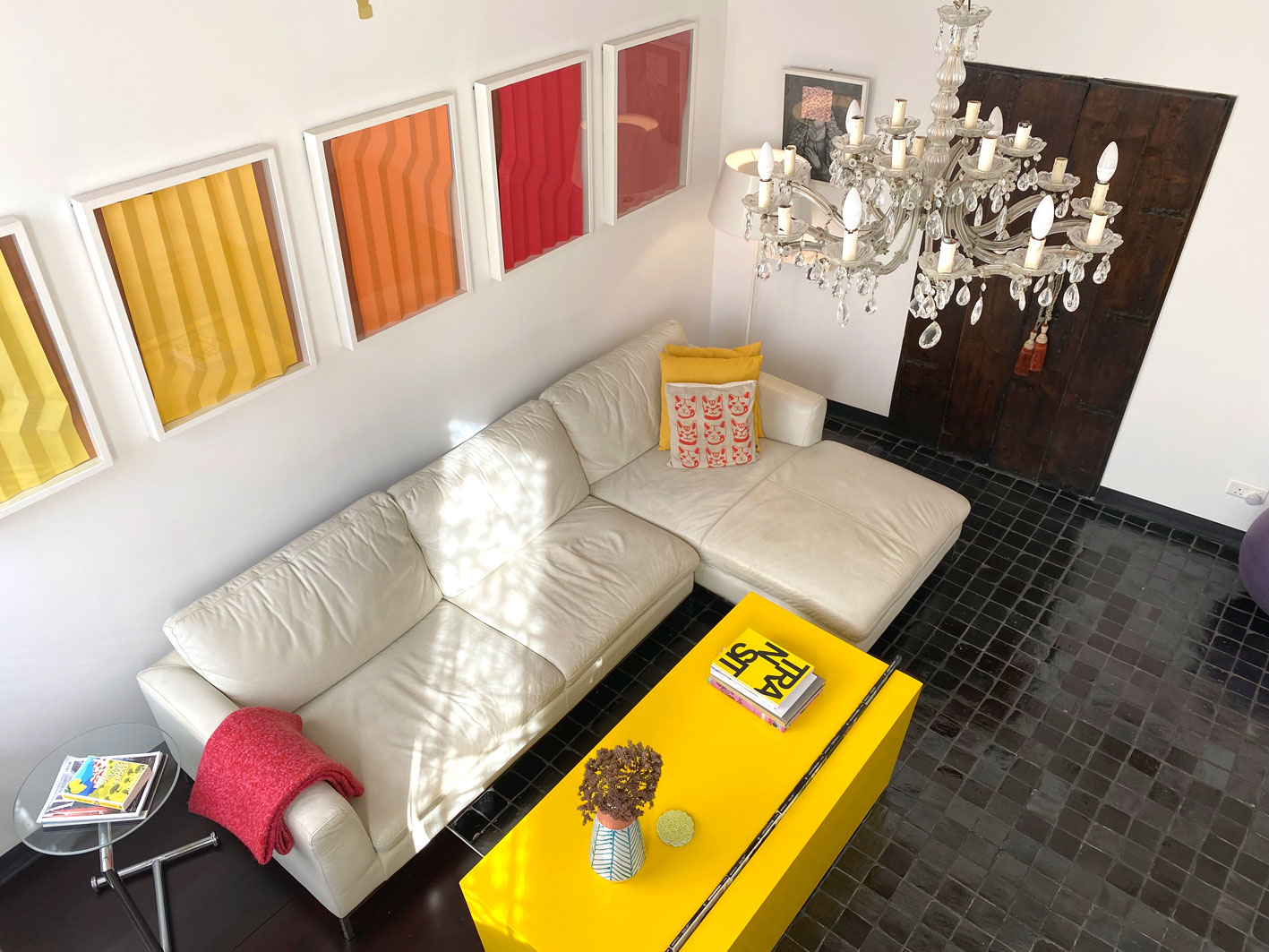 High view of sitting room showing white sofa, yellow coffee table, Moroccan handmade  tiles and colourful framed pictures on wall. Malta passport