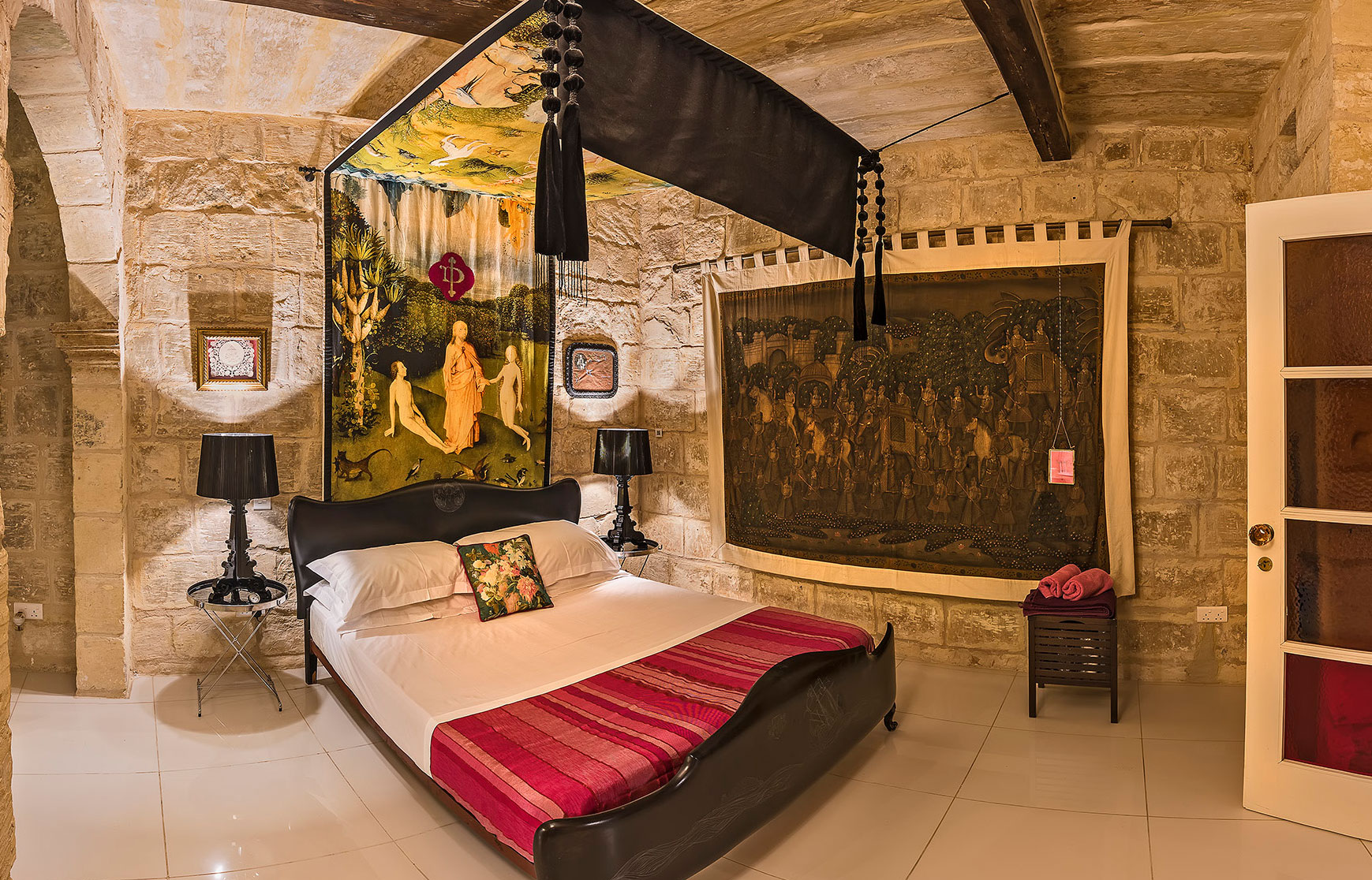 The bedroom with its original wooden beams and exposed stone walls in this historic Malta property was originally the house chapel.