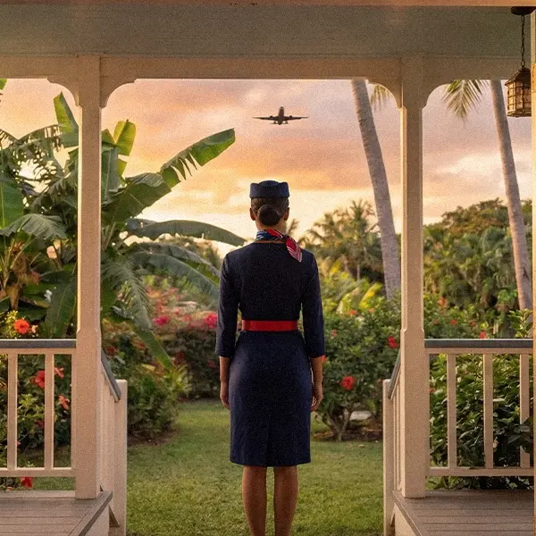 Hôtesse de l'air regardant un couché de soleil face à un jardin luxuriant typique des DROM