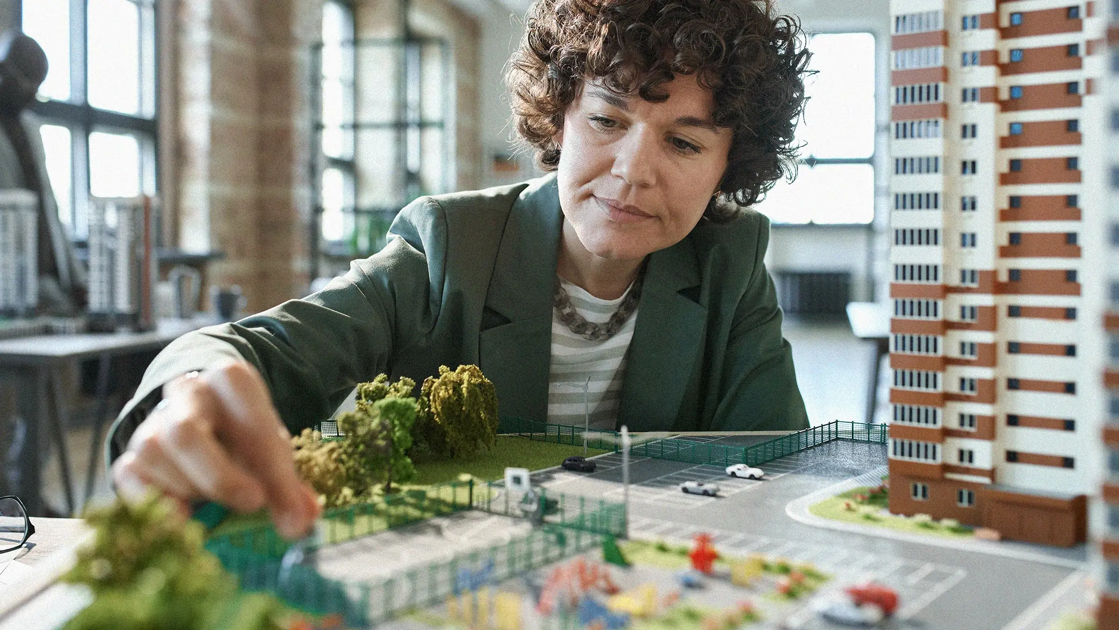 Femme ajustant une maquette architecturale détaillée, réalisation photo de l'agence de publicité EXI."