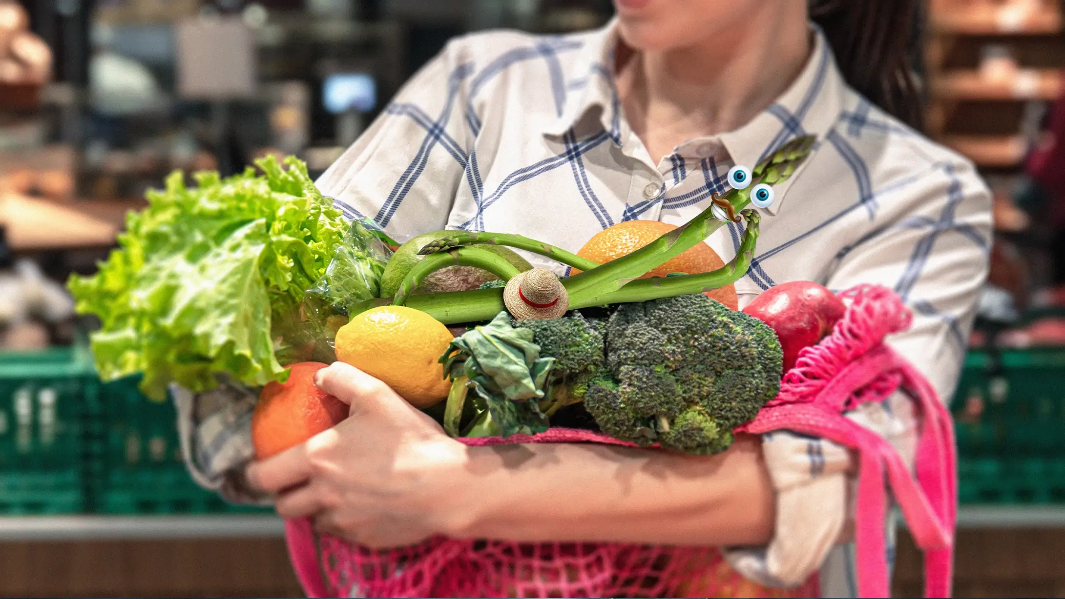 Image d'une personne portant des fruits et légumes dans ses bras dont une asperge avec des yeux et une bouche