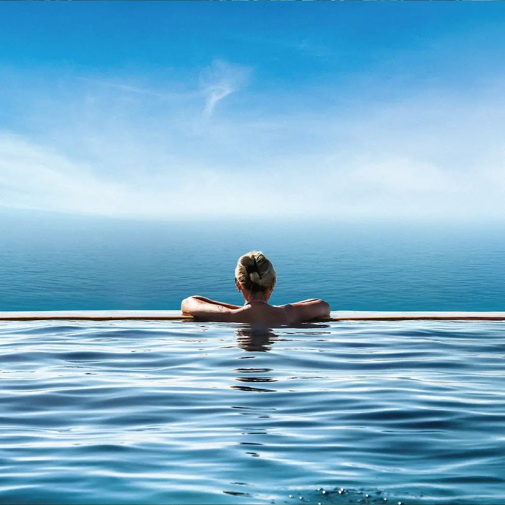Une femme se baignant dans une piscine à débordement avec une vue panoramique sur le Morne à l'ile maurice