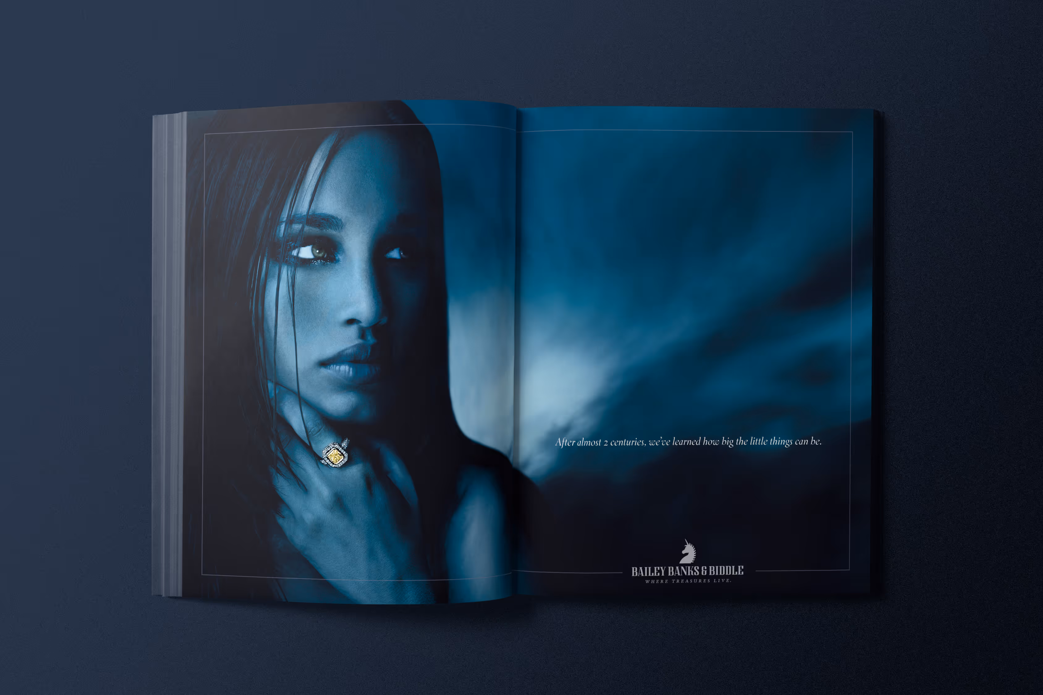 Magazine spread for Bailey, Banks & Biddle. Stylized blue to highlight the jewelry on a model. A yellow gemstone ring.