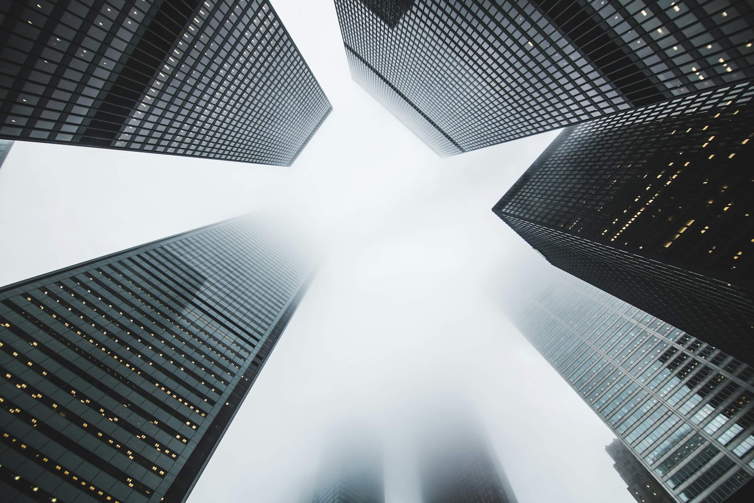 Looking up at glass office towers against a white sky
