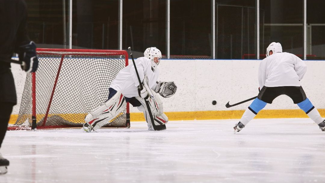 Ice hockey goalie facing a player during practice, emphasizing the importance of keeping rosters strong and healthy.
